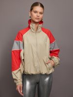 Model is wearing red, grey, and gold track jacket