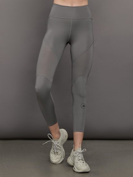Model wears high-rise grey leggings with a wide elastic waistband, laser-cut perforations, and a small back pocket.     