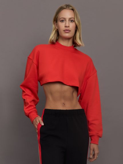 Model wears red cropped sweatshirt with a loose fit, ribbed edges, and a back cut-out detail.