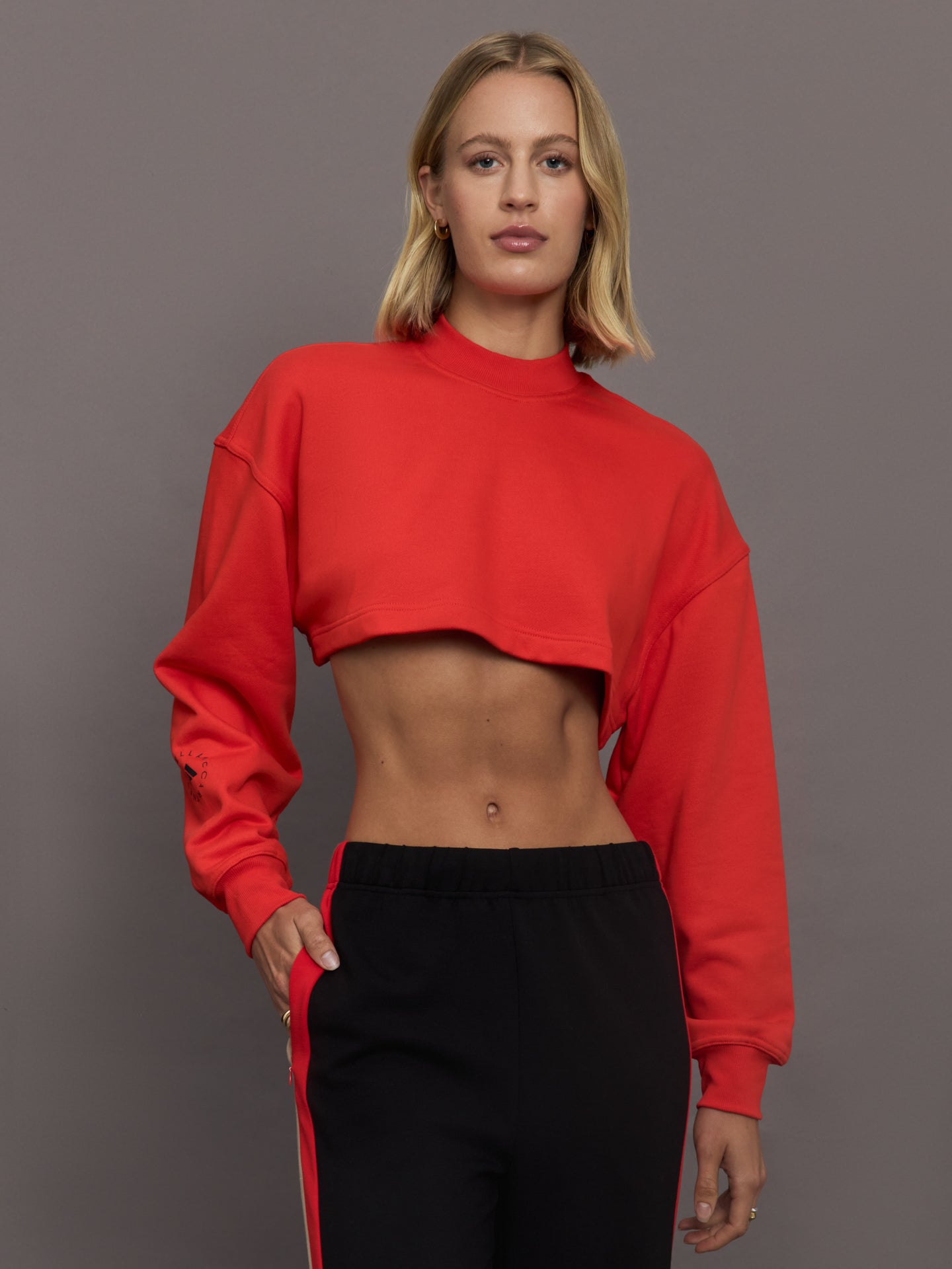ADID-JJ2574-REDRED-aSMC-trueCasuals-Cropped-Sportswear-Sweatshirt-color-Active-Red_10996-Edit Model wears red cropped sweatshirt with a loose fit, ribbed edges, and a back cut-out detail.