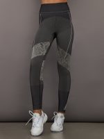 Person wearing black and gray leggings with a patterned snakeskin design on a gray background