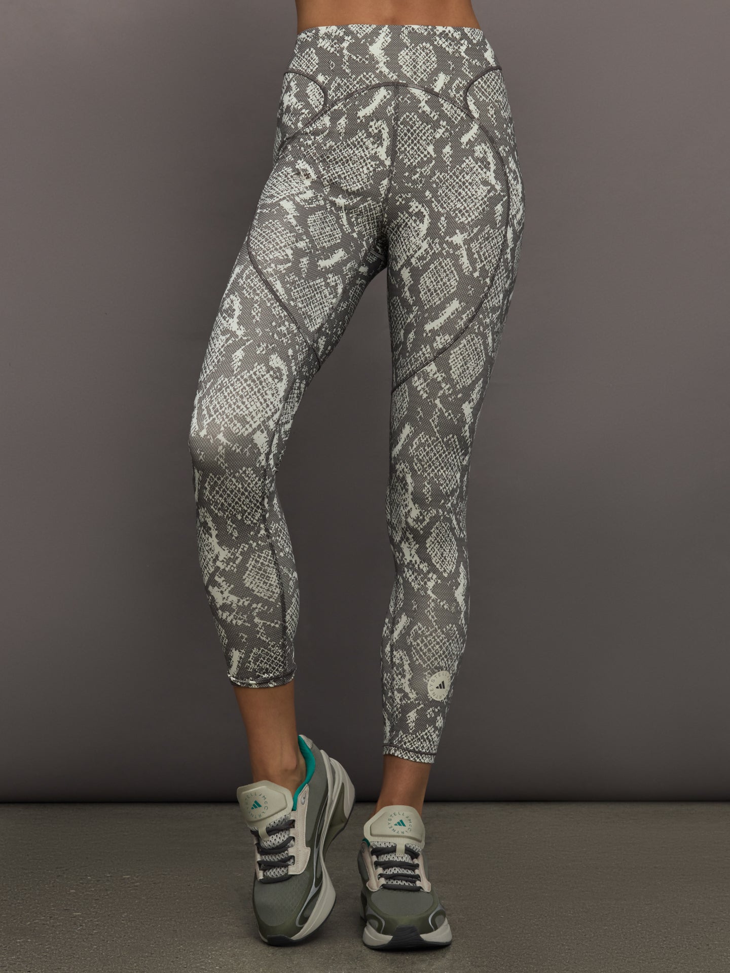 ADID-JW4556-IVRYOFFWHI-aSMC-TruePurpose-Training-Leggings-P-color-Almond-Milk-Smc-Charcoal_11541-Edit Model wearing grey and white snake print leggings.