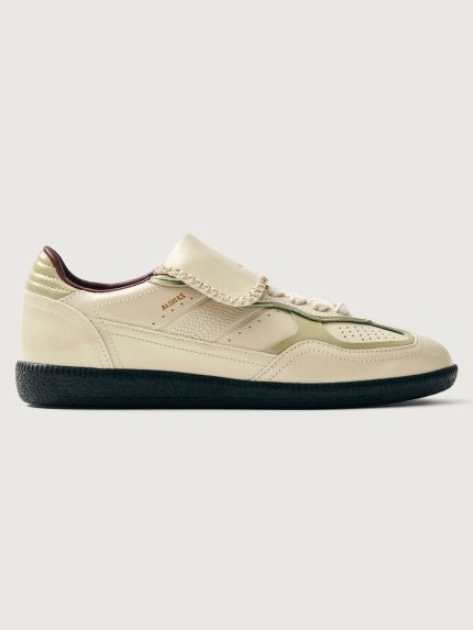 Creme colored low top lifestyle sneaker with black sole & gold/creme heel detailing.