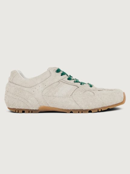 Grey sneaker with green and black laces.