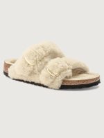 A pair of beige teddy shearling slippers with two adjustable straps and metal pin buckles, featuring an anatomical cork-latex footbed and a platform sole.