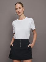 Model wears a basic white tee shirt with ringer neck and the word "Bandier" across the sleeve.