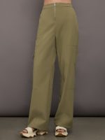 Model wears a pair of olive/khaki colored mid-rise wide leg cargo pants with cargo pockets on side, silver zipper in front.