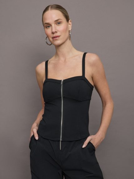Model wears a black tank top with corseted silhouette and silver zipper extending from top to bottom in center. 