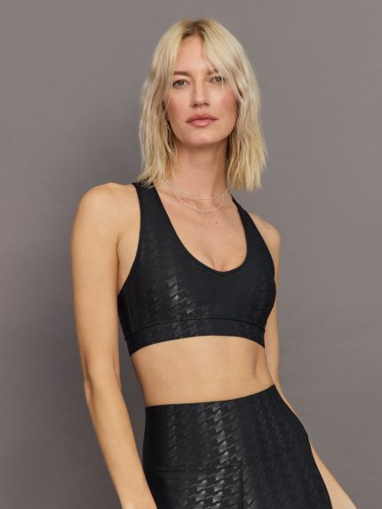 Model wears a vneck black bra with a shiny houndstooth all over print.