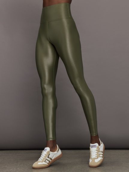 Model wears high-rise, full-length olive leggings with a glossy finish.