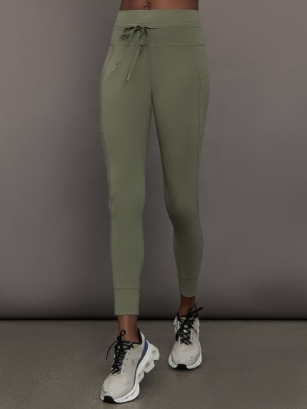 Model wears a pair of high waisted leggings in army green olive with a drawstring at waist. 