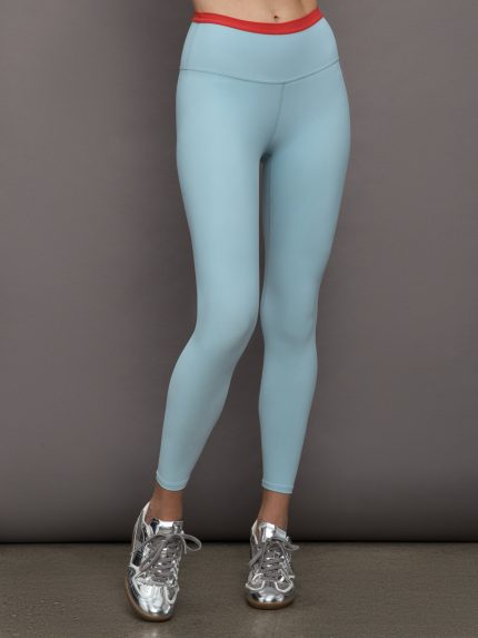 Model wears a light blue performance legging with a red waistline.