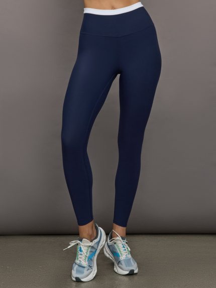 Model wears a buttery soft high waisted navy legging with thin white waistband.