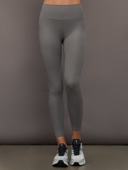 Model wears high-rise leggings in steel grey with a ribbed texture, with a wide waistband and a form-fitting silhouette.