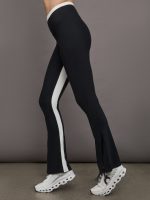 Model wears high waisted black bootcut legging with white stripe along the inseam.
