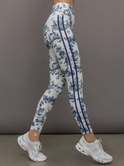 Model wears a pair of high waisted white leggings with navy toile print allover, and thick navy lines down the sides. 