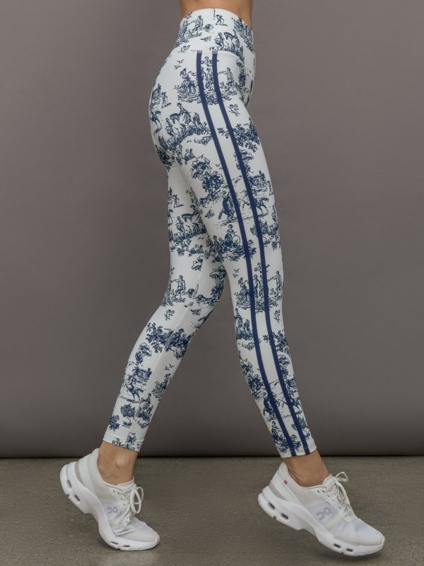 Model wears a pair of high waisted white leggings with navy toile print allover, and thick navy lines down the sides.