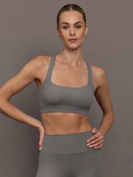 Model wears steel grey-colored racerback bra with a ribbed texture, square neckline, and wide straps that merge at the back.