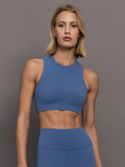 Model wears a periwinkle blue buttery soft cropped sports bra with an asymmetric open back.