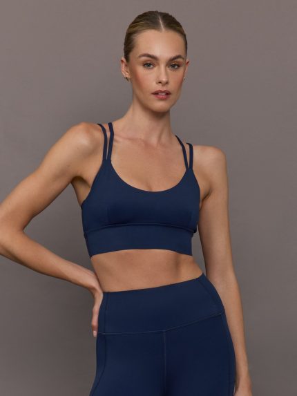 Model wearing navy sports bra with two straps.
