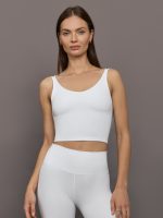 Model wears white ribbed V-neck tank with a sculpted and cropped fit.