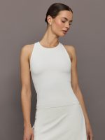 Model wears white high-neck active tank with a racerback design and smooth, fitted finish.