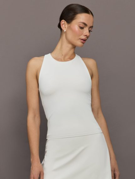Model wears white high-neck active tank with a racerback design and smooth, fitted finish.     