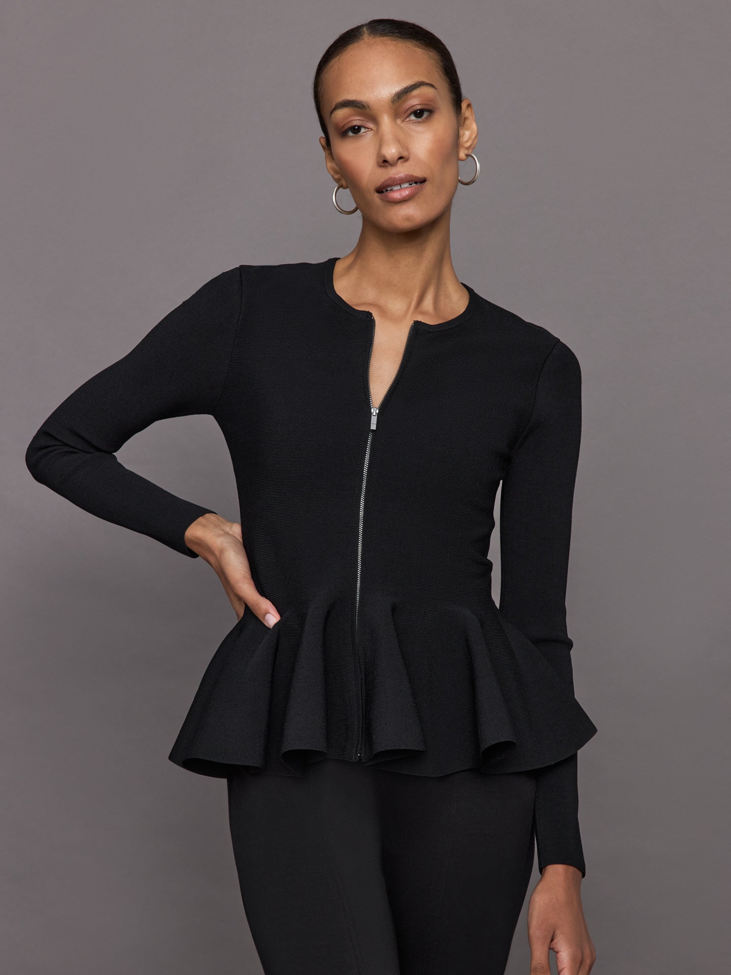 CARB-YD563-BLK-24FAL-Peplum-Zip-Up-color-Black_42-Edit Model wears black long-sleeve zip-up sweater with a fitted bodice and flared peplum hem.