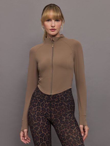 Model wearing a beige mock neck corset zip top with thumb holes.