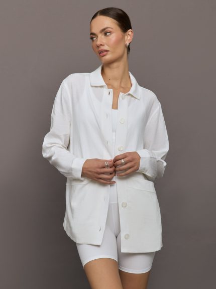 Model wears white collared linen jacket with buttons down the front and long sleeves.