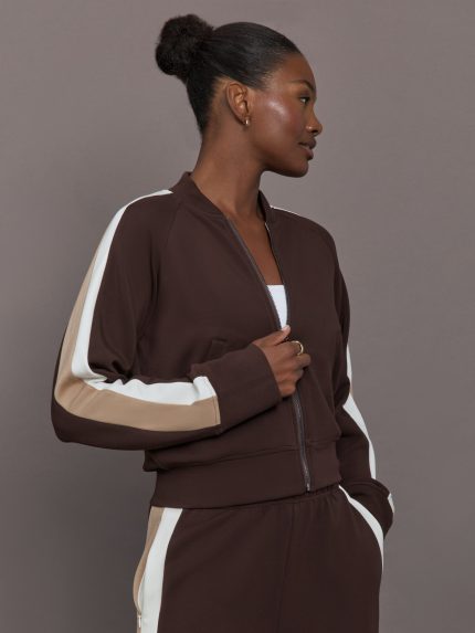 Model wearing brown bomber with white and beige stripes on the sleeves.
