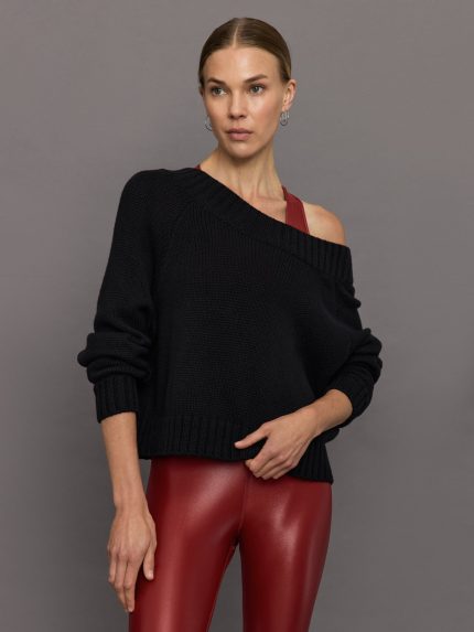 Model wears black, loose-fitting knit sweater with long sleeves and a wide neckline, worn off one shoulder.