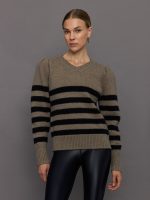 Model wears striped cream and black sweater with puffed sleeves and a relaxed fit.