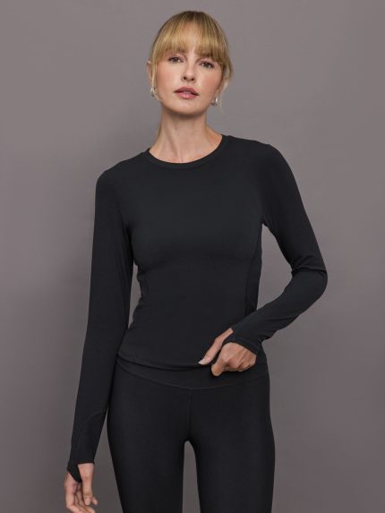 Model wears black long-sleeve fitted top with a crew neckline and smooth fabric.