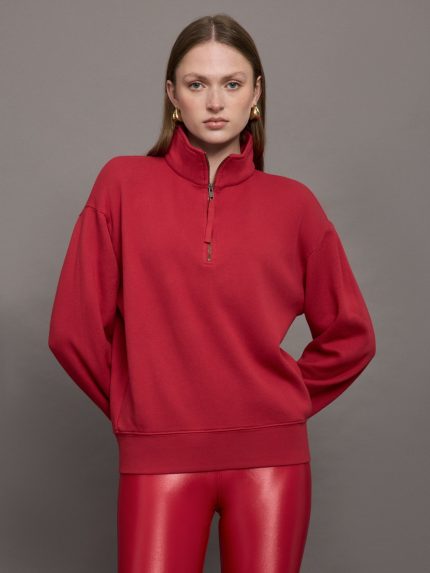 Model wears a fire engine red long sleeve half zip sweatshirt.
