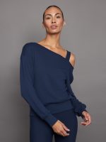 Model wears a navy, slouchy French terry sweatshirt with an off-the-shoulder, raw-edged asymmetrical neckline and a relaxed fit.