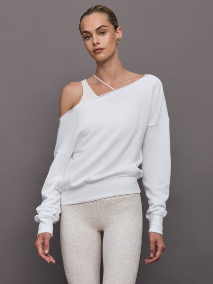 Model wears a white slouchy, off-the-shoulder French terry sweatshirt with a raw-edged asymmetrical neckline and a relaxed, roomy fit.     