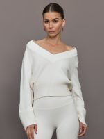Model wears a white v neck bell sleeved sweater.