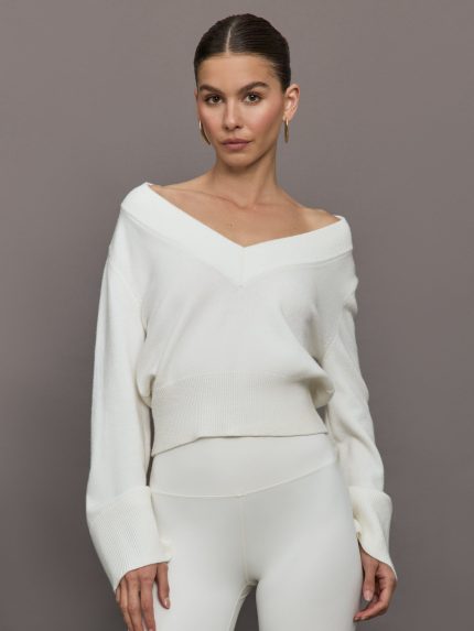 Model wears a white v neck bell sleeved sweater.