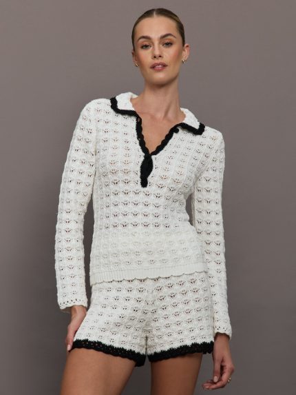 Model wears Ivory long sleeve polo top with black outlining the collar.