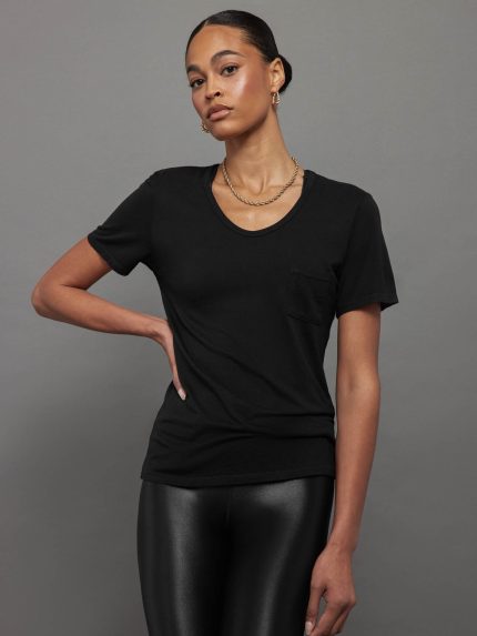 Model wears a black, short sleeve crewneck t-shirt with a front pocket and a relaxed, hip-length fit.