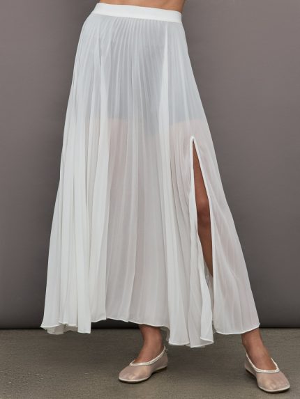 Model wears a long, sheer mesh pleated skirt with an elastic waistband and slit on one side.
