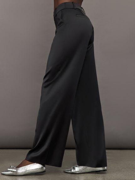 Model wears black satin pants with a relaxed fit.