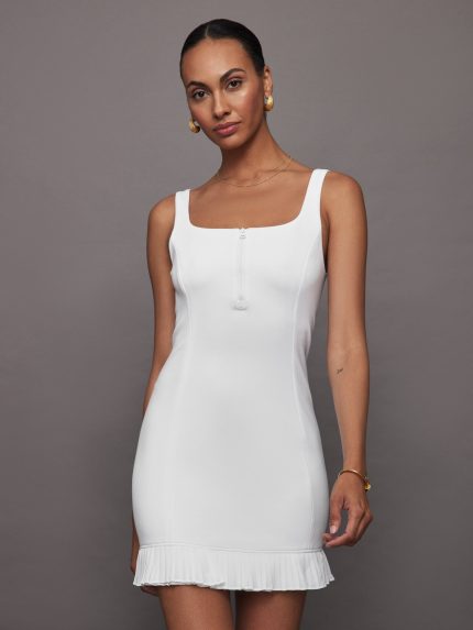Model wears white sleeveless tennis dress in a fitted bodice with a pleated skirt.