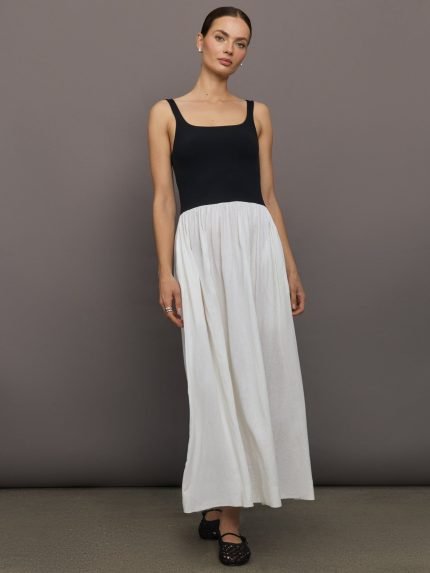 Model wears sleeveless dress with a black fitted top and white flowy bottom.