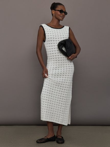 Model wearing a long ivory crochet dress with black accents