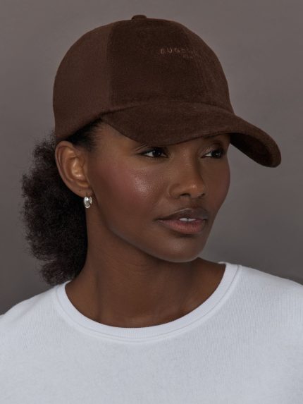 Model wearing a brown cap against a gray background