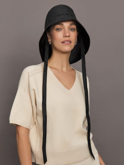 Model wears a black bucket hat with long braided straps.