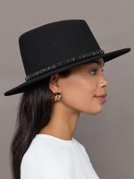 Model wearing a black hat with a decorative band.