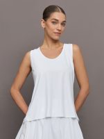 Model wears a loosely fitted round neck white tank top.